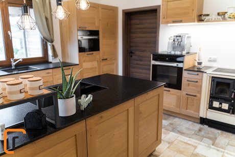 Landhausküche in wildeiche mit dunkler Arbeitsplatte und altem Holzherd