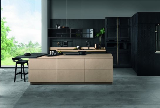 Inselküche in sandfarbener Betonoptik mit schwarzen Fronten aus Holzfurnier