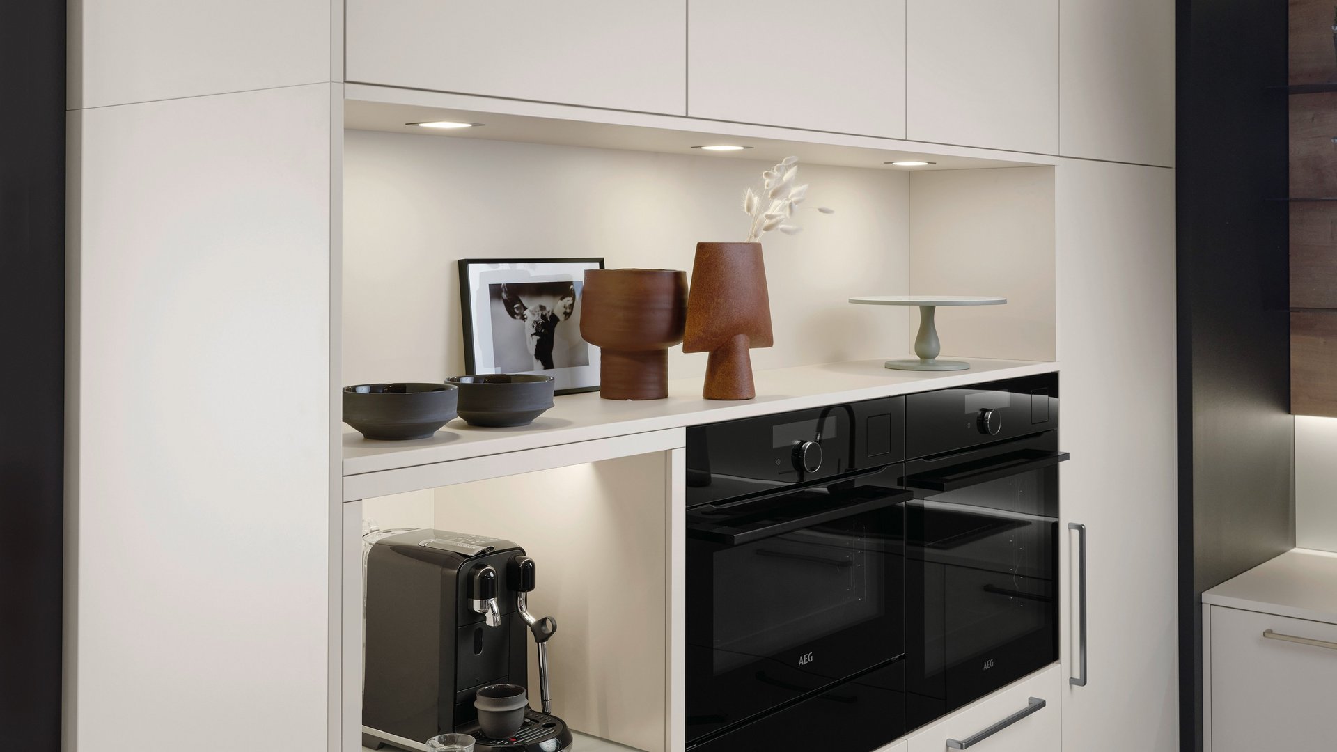 ewe Nuova/Cemento in angora/patina bronze Helle Hochschrankgruppe mit einer Nische für Kaffeemaschinen, die Lade darunter für Kaffeezubehör ist geöffnet