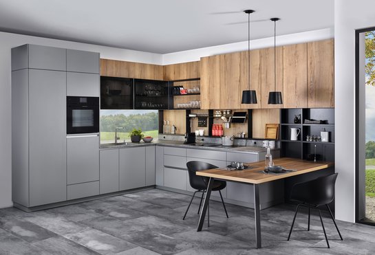 L-förmige Küche in zementgrau mit Rückwand in Holzoptik mit angebautem Esstisch