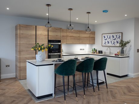 Weiße Inselküche mit Bar und schwarzen Barstühlen, mit Hochschränken in Holzoptik