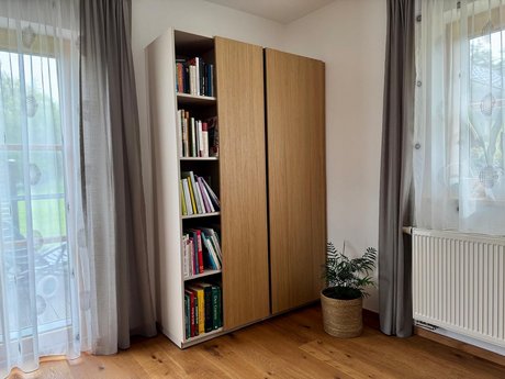 Hochschrank mit seitlich offenem Regal – Bücher und Pflanzen setzen wohnliche Akzente.