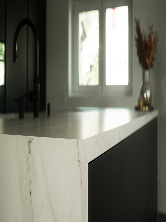 Kücheninsel in dunkelgrau mit umlaufender Arbeitsplatte in Marmor-Optik