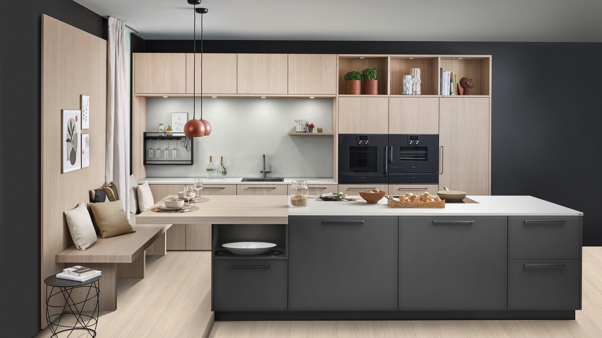 ewe Colora/Nordic in cameroon/eiche weiß nordic Große dunkle Kücheninsel vor einer Küchenzeile aus hellem Holz, links an der Insel ist eine Sitzbank