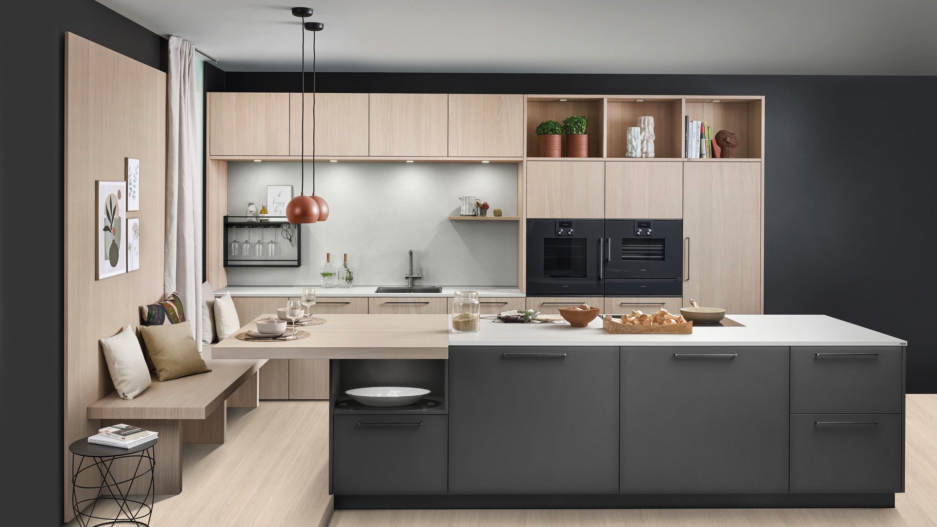 ewe Colora/Nordic in cameroon/eiche weiß nordic Große dunkle Kücheninsel vor einer Küchenzeile aus hellem Holz, links an der Insel ist eine Sitzbank