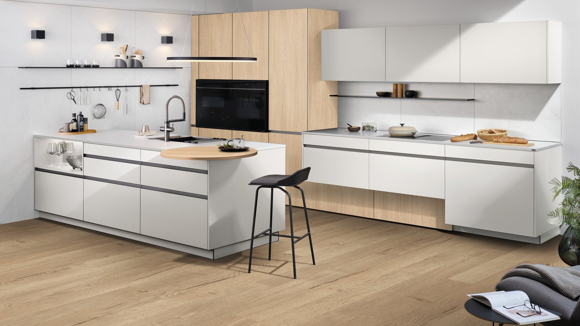 ewe GL30 in Aluminium edelstahlfarbig eloxiert gezeigt an ewe Nuova . ewe Sintesa in weiß . eiche hell, schräge Hauptansicht Offene Küche mit Kochinsel, weißen Fronten und Holzschränken.