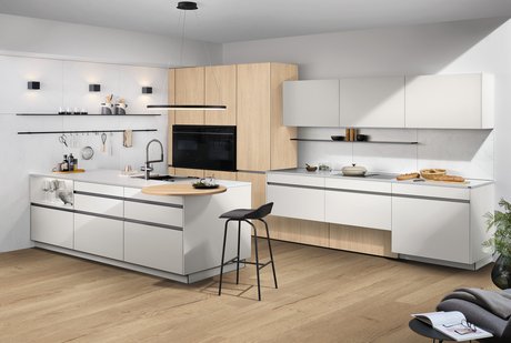 Offene Küche mit Kochinsel, weißen Fronten und Holzschränken.