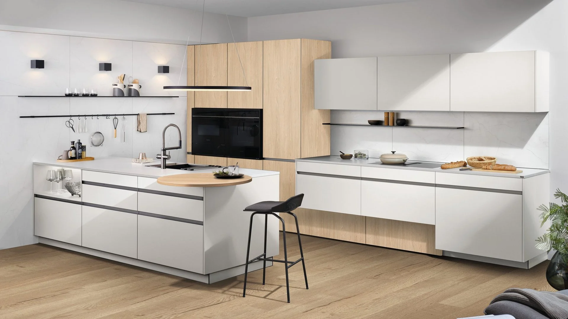 ewe GL30 in Aluminium edelstahlfarbig eloxiert gezeigt an ewe Nuova . ewe Sintesa in weiß . eiche hell, schräge Hauptansicht Offene Küche mit Kochinsel, weißen Fronten und Holzschränken.