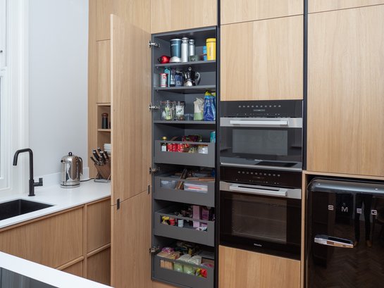 Hochschrankgruppe in heller Holzküche mit geöffnetem Vorratsschrank mit grauen Laden