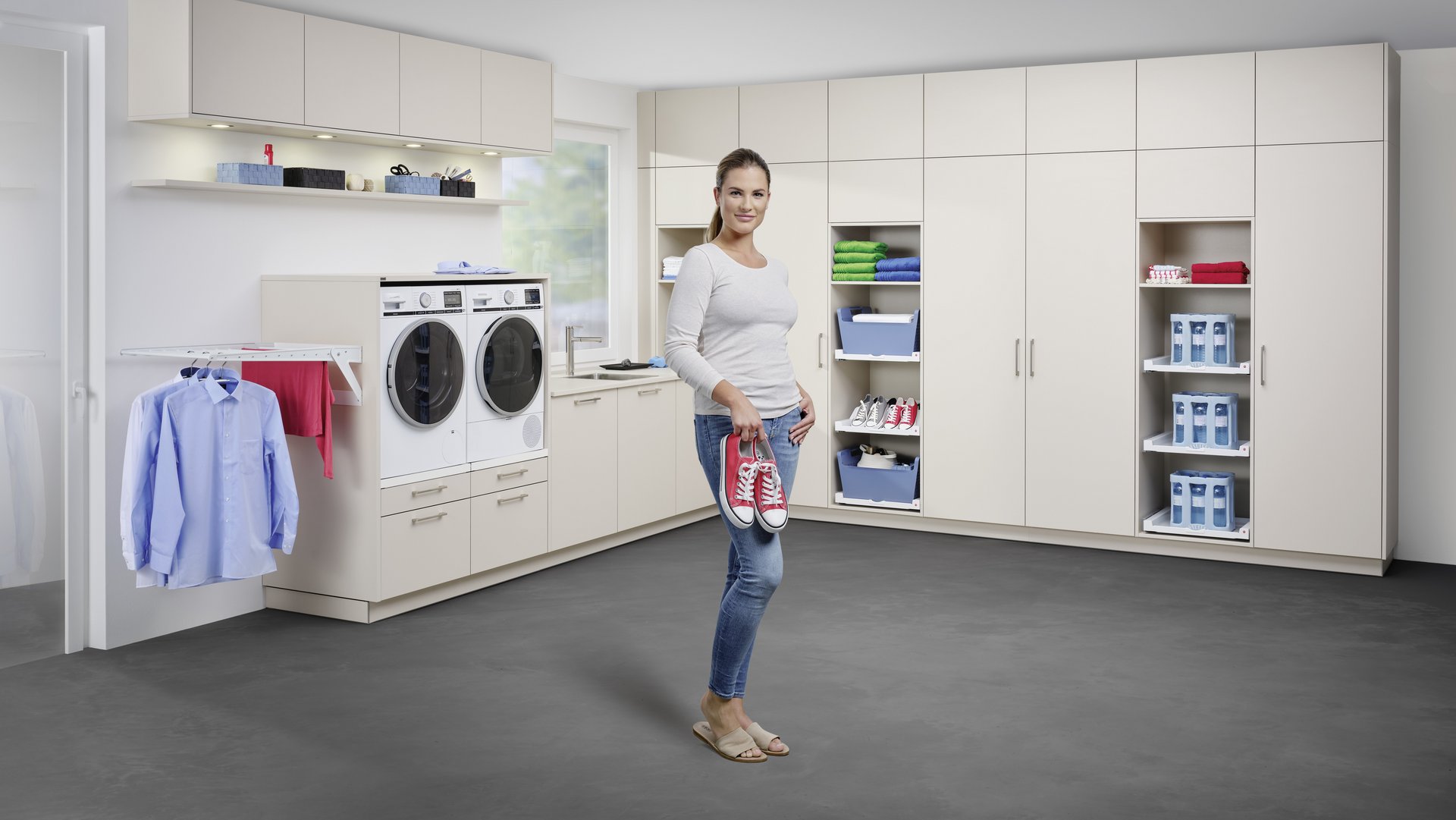 ewe store4more® - der Hauswirtschaftsraum von ewe Eine Frau steht vor einem L-förmigen, großen Hauswirtschaftsraum mit weißen Fronten