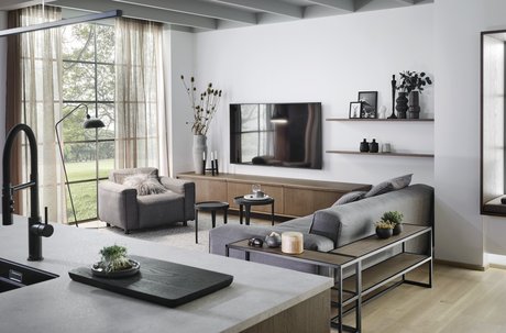 Wohnzimmer hinter Kücheninsel mit Sofa, Sideboard und großem Fenster