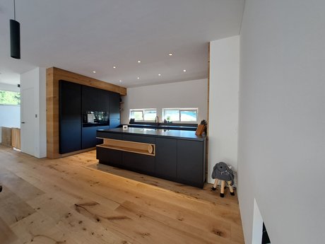 Inselküche in schwarz mit Holznische in der Kücheninsel und schwarzer Hochschrankgruppe