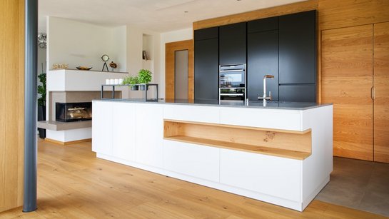 Weiße Kücheninsel mit Nische mit Holzverkleidung und dunklen Hochschränken