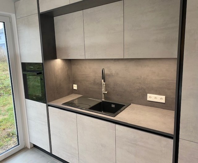 Rückwärtige Küchenzeile einer kleinen Inselküche in heller Betonoberfläche mit großer schwarzer Spüle