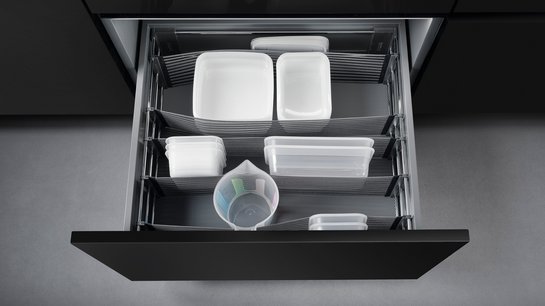 Offene Küchenschublade mit elastischen Bändern zur Trennung des Inhalts