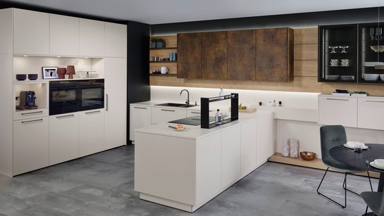 Helle U-förmige Küche mit bronzefarbigen griffen und Oberschränken in patina bronze.