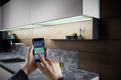 Zwei Hände, die ein Smartphone halten, steuern die Küchenbeleuchtung per App