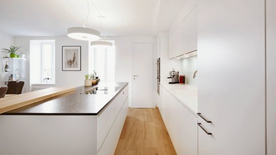 Weiße Inselküche mit dunkler Steinarbeitsplatte und Barplatte aus Holz