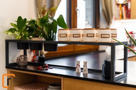 Einfaches Stellregal aus schwarzem Metall auf einer Kücheninsel mit Holzfronten