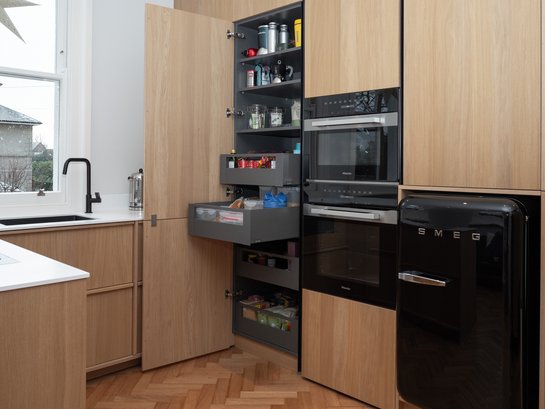 U-förmige Küche in bergeiche, rechts eine Hochschrankgruppe mit geöffneter Tür und offenen Schubladen