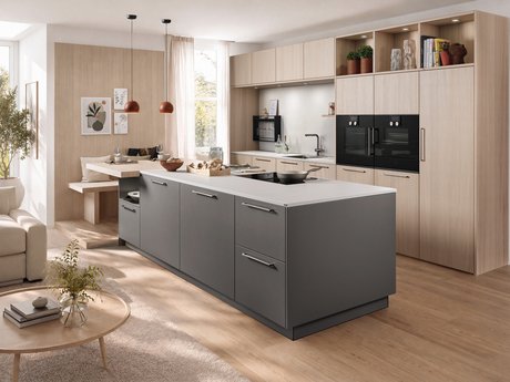 Graue Kücheninsel mit angebauter Sitzbank und Hochschränken aus hellem Holz