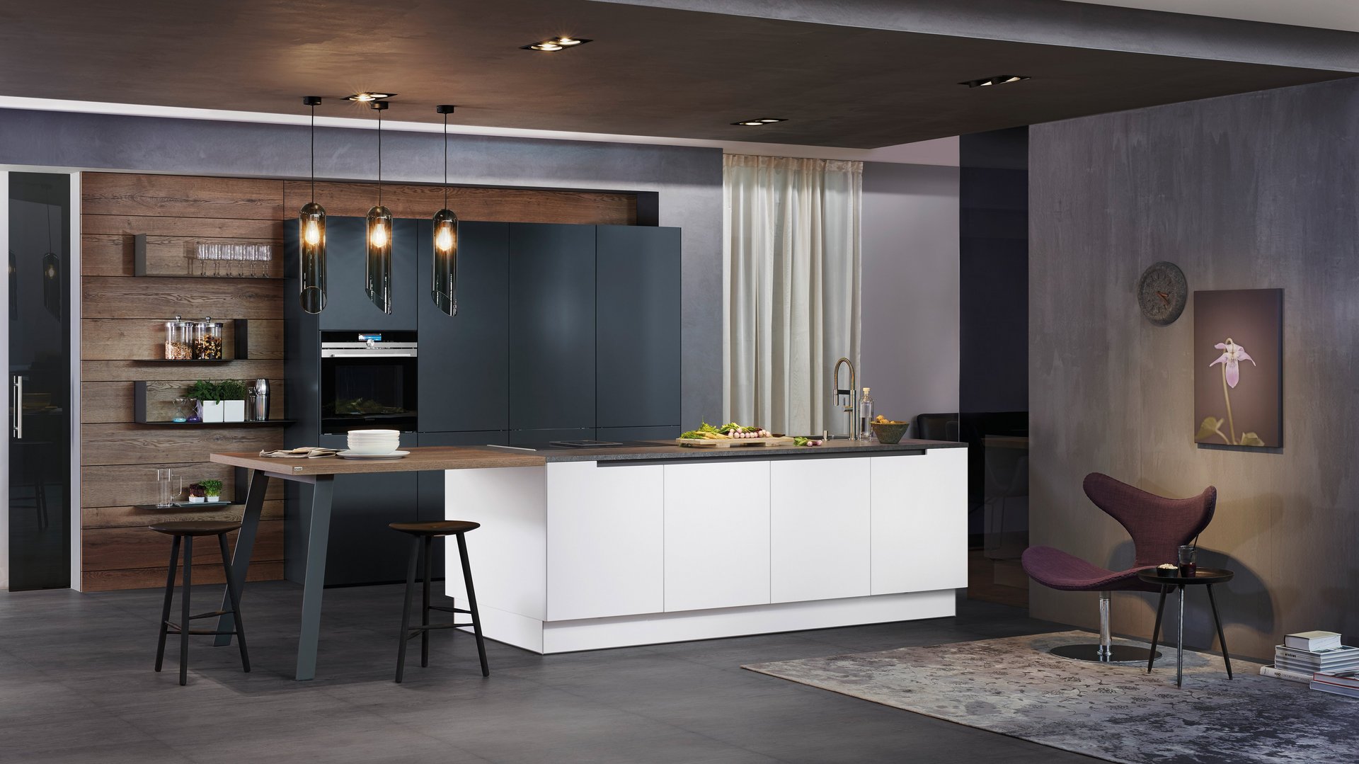 ewe50 in weiß . anthrazit, schräge Hauptansicht Weiße Inselküche mit angebautem Tisch mit Hockern, dahinter Hochschränke in anthrazit