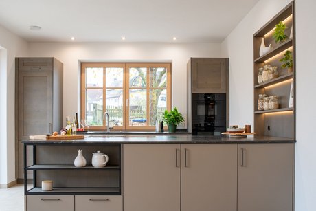 Inselküche mit moderner Kücheninsel in lehmbraun mit integrietrer Nische mit Metallrahmen in schwarz