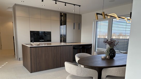 Moderne Essplatzgruppe, dahinter Inselküche in Holzoptik und grau