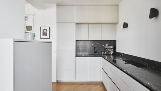 Die deckenhohen Hochschränke und Oberschränke nutzen den Raum optimal aus und sorgen für großzügigen Stauraum.