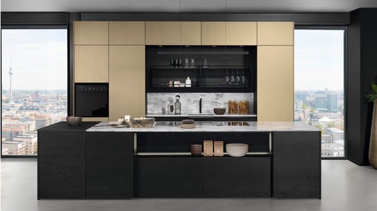 Inselküche mit schwarzer Kücheninsel mit Holzfronten und bronzefarbigen Hochschränken