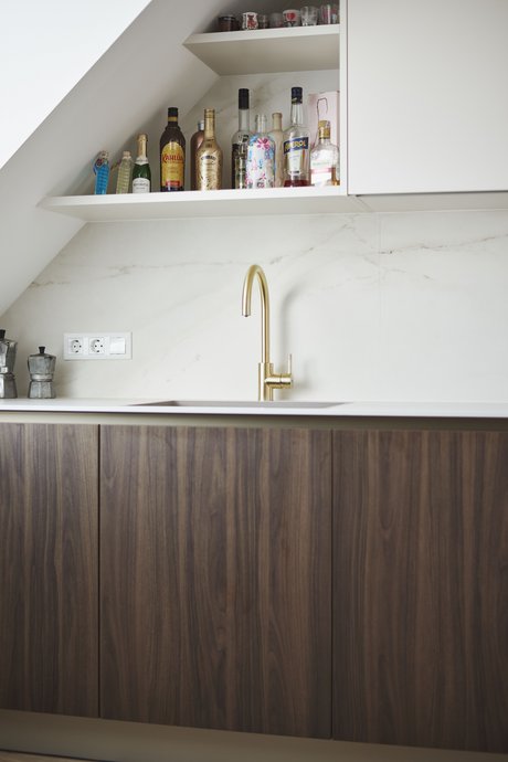 Die goldfarbene Edelstahlarmatur harmoniert elegant mit der dezenten Musterung der Rückwand – ein edles Detail mit Funktion und Stil.