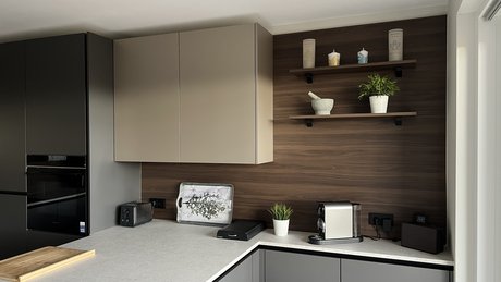 Detailansicht der Küchenzeile mit Oberschränken in sahara metallic und Rückwand in nuss pavia.