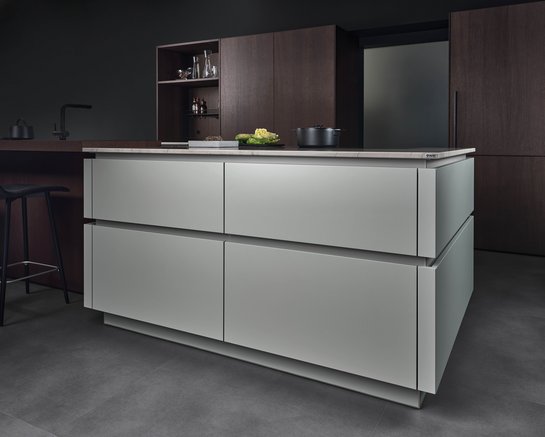 Kücheninsel in der gräulichen Farbe matcha latte mit farblich passend lackierten Griffmulden