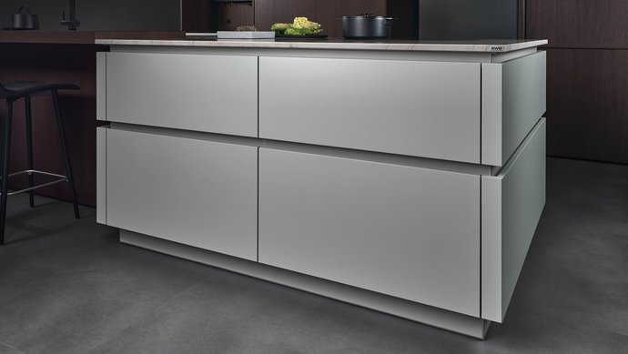 Kücheninsel in der gräulichen Farbe matcha latte mit farblich passend lackierten Griffmulden