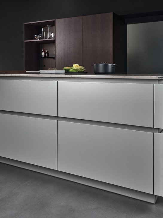 Kücheninsel in der gräulichen Farbe matcha latte mit farblich passend lackierten Griffmulden