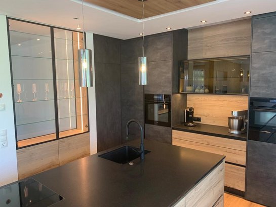 Moderne grifflose Küche mit markanter Insel im Modell ewe Sintesa in bergeiche und Hochschränken in Concreto beton schiefergrau.