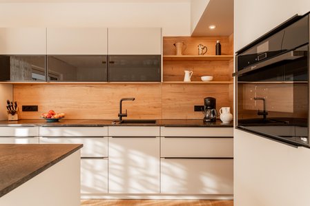 Helle Küchenzeile mit Rückwand in Holzoptik und schwarzer Arbeitsplatte