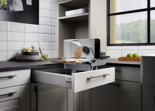 Geöffnete Küchenschublade in weißer Holzküche mit integriertem Allesschneider