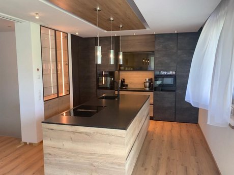 Moderne Küche mit Hochschrankgruppe im Modell ewe Concreto beton schiefergrau mit hochgestelltem Backofen und zusätzlichen Stauraummöglichkeiten.