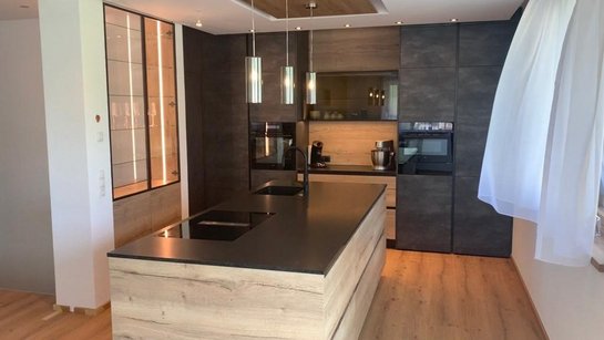 Moderne Küche mit Hochschrankgruppe im Modell ewe Concreto beton schiefergrau mit hochgestelltem Backofen und zusätzlichen Stauraummöglichkeiten.