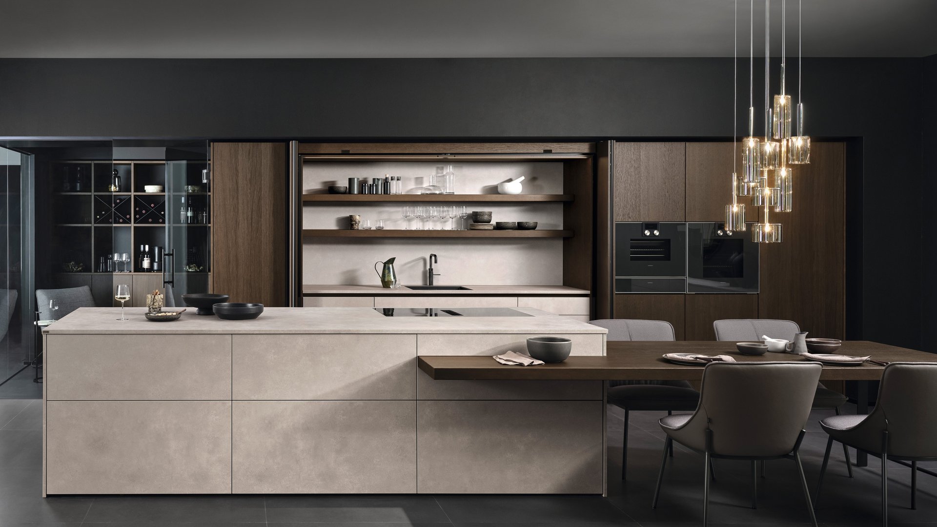 ewe Concreto in beton sand . eiche tobacco Kücheninsel in Betonoptik mit angebautem Esstisch und Hochschränken in dunklem Holzfurnier