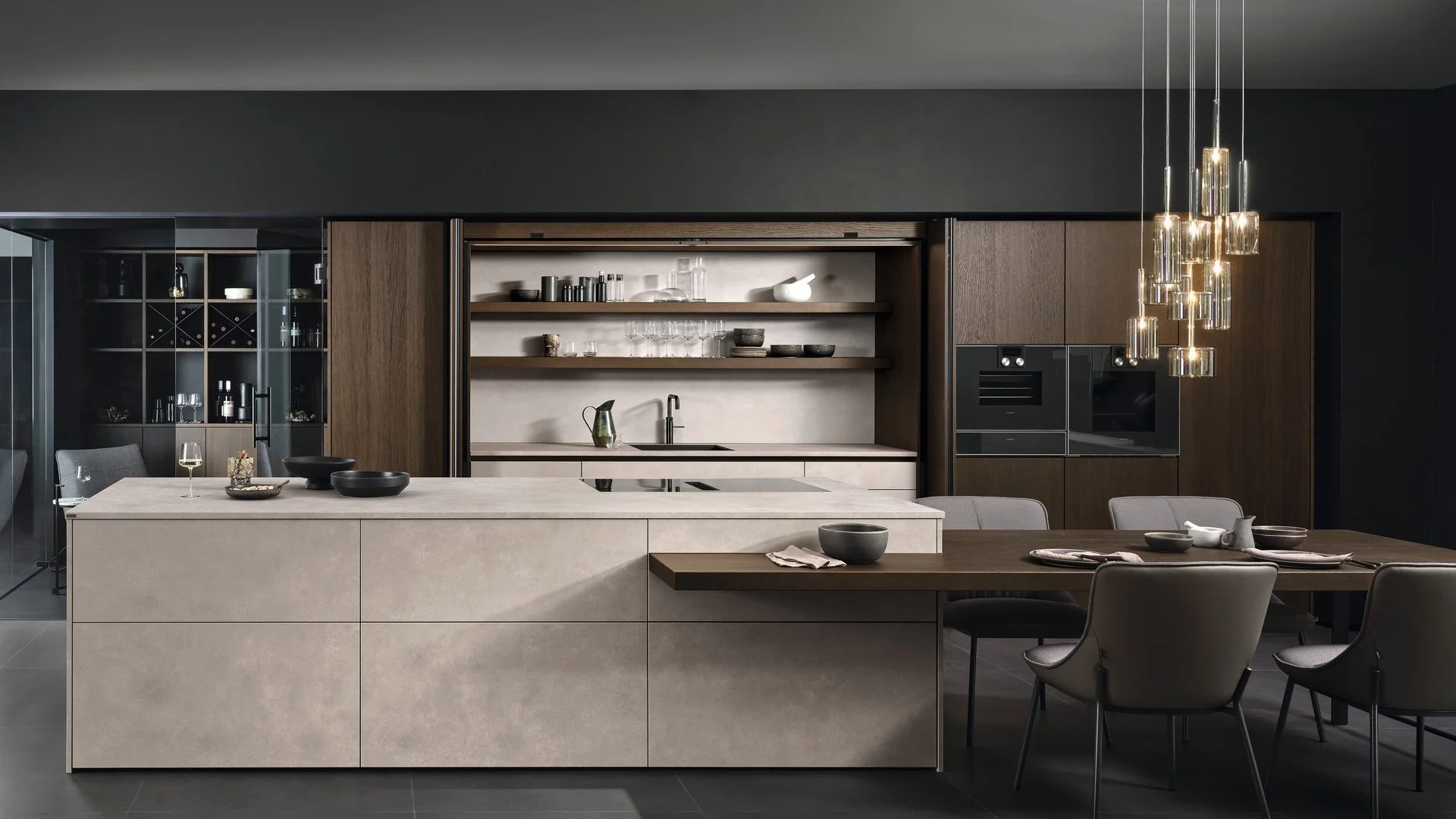 ewe Concreto in beton sand . eiche tobacco Kücheninsel in Betonoptik mit angebautem Esstisch und Hochschränken in dunklem Holzfurnier