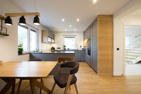 Graue U-förmige Küche hinter einem Esstisch mit Stühlen