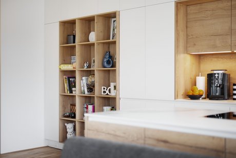 Für ein persönliches Feeling wurde in dieser Inselküche ein Wandregal aus Eichenholz eingebaut.