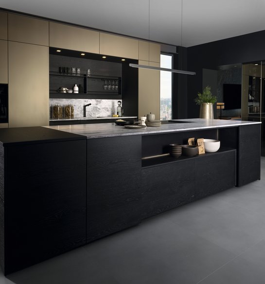 Kücheninsel in schwarzem Holzfurnier, dahinter Hochschränke in bronze