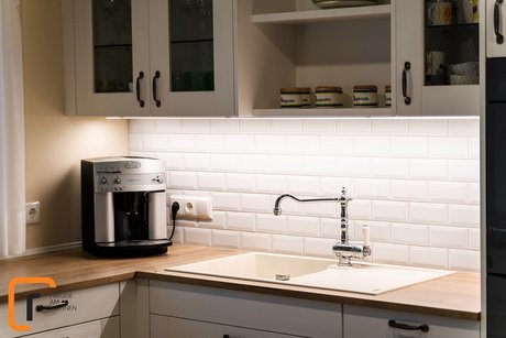 Detail aus einer Küche, der Spülbereich mit weißer Spüle, darüber Oberschränke