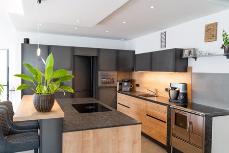 ewe Eisenfels/Sintesa in eisen/eiche umbria | Riegler - Freude am Wohnen Inselküche in eiche umbria mit Hochschränken eisenfärbig, darin eine versteckte Tür zur Speisekammer