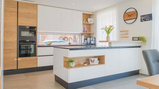 Die warme Eiche und die LED-Lichtleiste unter den Oberschränken schaffen eine einladende Atmosphäre – modern und gemütlich zugleich.