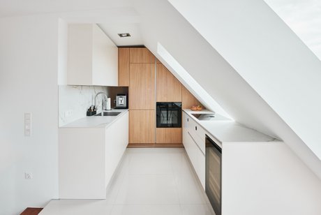Weiße Küche bestehend aus zwei Küchenzeilen mit holzfarbenem Hochschrank