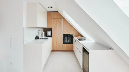 Weiße Küche bestehend aus zwei Küchenzeilen mit holzfarbenem Hochschrank